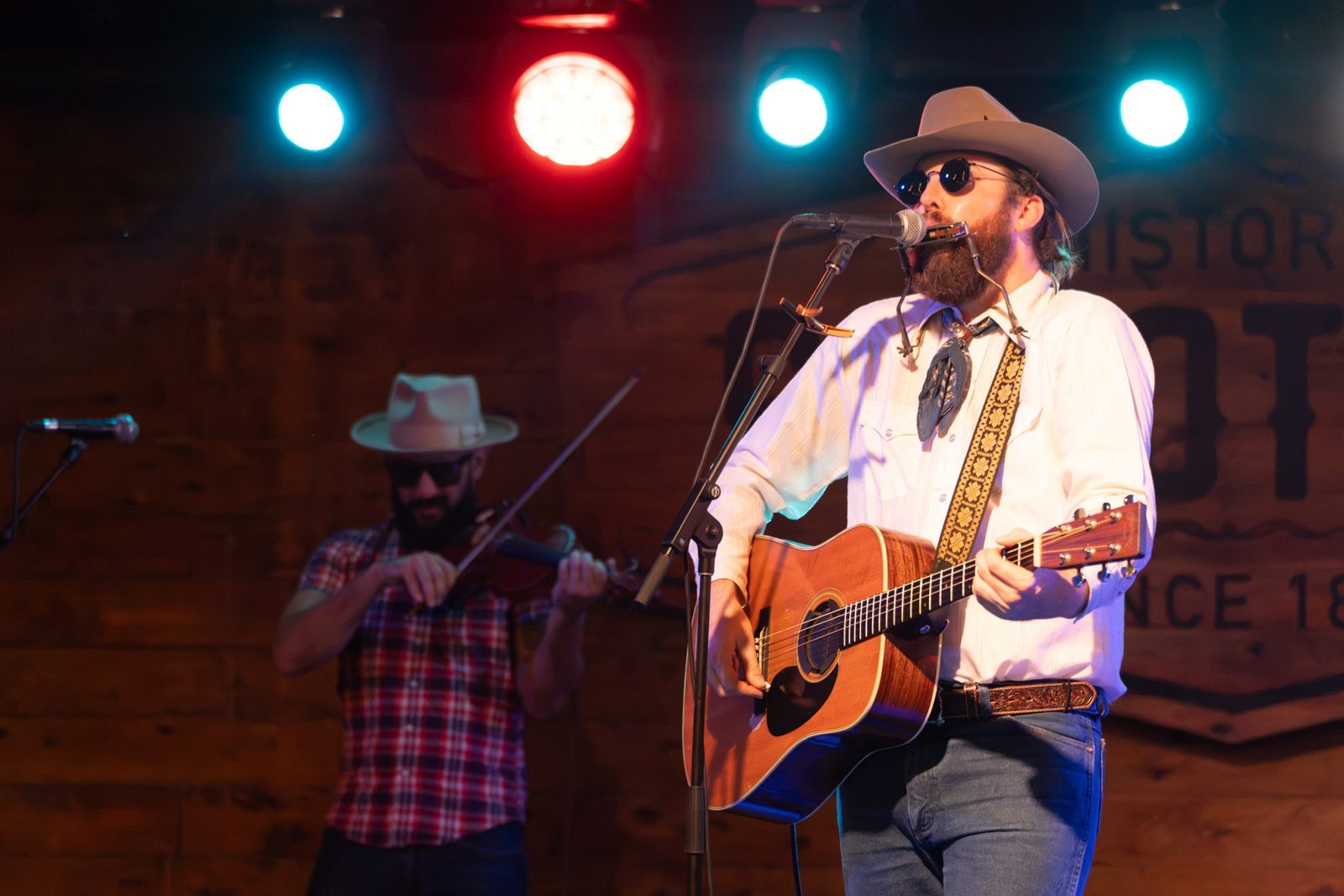 A country band playing fiddle and guitar on the Scoot Inn stage
